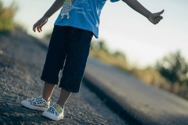 The boy stood on the light road in the morning.