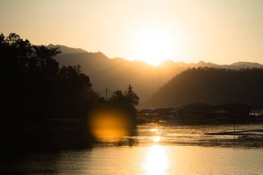 Resort in the middle of the water with mountains surrounded by nature with the sunlight in the evening.