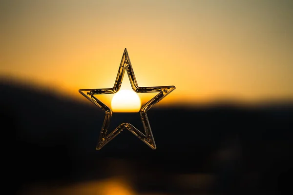 Floating stars on golden light background with sunset in the middle.