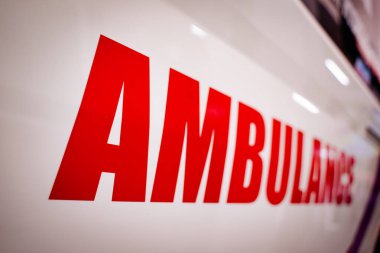Kırmızı harfli beyaz bir ambulansın yan görüntüsü.
