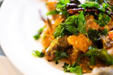 Çıtır domuz fesleğeni, beyaz tabakta lezzetli Tayland yemeği servis edilmeye hazır..