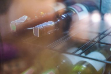 Raftaki şarap şişeleri yayılmış ışık kullanıyor..