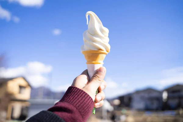 Stock image ice cream in hand bright sky background.