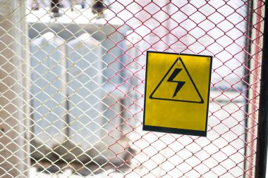 Tehlikeli bölgelerdeki çelik ızgarada yüksek voltajlı tehlike işareti.