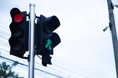 Yayalar için yeşil ve kırmızı trafik ışıkları yayaların caddeyi geçmesine izin vermek için durur. Beyaz gökyüzü arka planında.