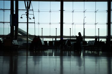 Havaalanı ve havaalanı terminalindeki yolcuların silueti..