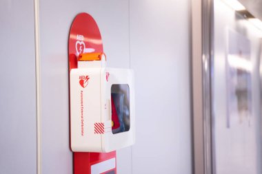 Beyaz duvara monte edilmiş otomatik dış defibrilatör.