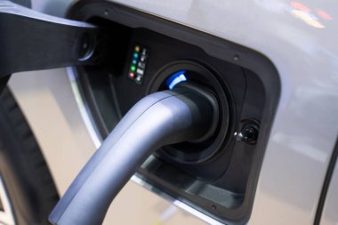 Elektrik kablosu fişini modern teknolojiye sahip elektrikli araba EV arabasına takın UI sürdürülebilir eko enerji kavramı.