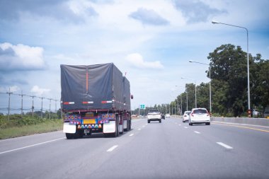 Otoyolun kenarına park etmiş karavanlı büyük bir kamyon, parlak gökyüzü arka planı..