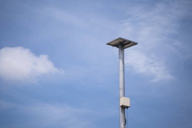 Acil durumlarda enerji sağlamak için güneş panelleri olan bir kutup. Mavi gökyüzünün arka planında.