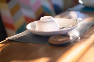 Bardaklar ve tabaklar yemek masasının arka planında..