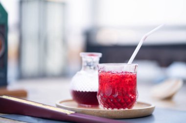 Kırmızı içeceği, yemek masasındaki ahşap tepside içilmeye hazır buzla tazeliyorum..