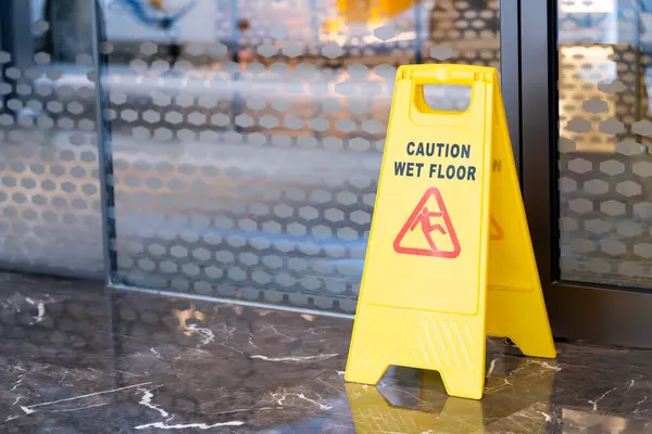 The yellow sign on the floor marks the area being cleaned. The floor is wet, be careful, it\'s slippery.