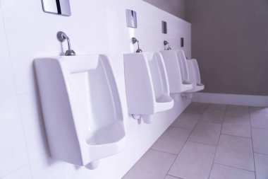 Public restroom. Row of urinals. The urinal design is white ceramic. Modern men's bathroom. clipart