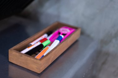 Çok renkli kimyasal kalemler alüminyum bir rafta ahşap bir kutuya yerleştirilmiş çatal bıçaklar..