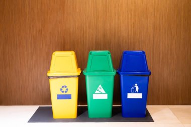 Sarı, yeşil ve mavi plastik çöp bidonları ayrı tür geri dönüşümlü atık, ıslak atık, genel atık, çevre koruma kavramı.