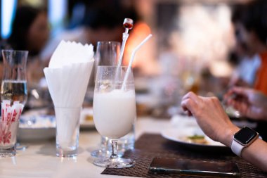 Yemek saatinde masada pipetle kokteyl bardağında soğuk yoğurt içeceği..