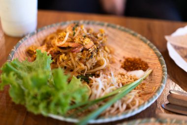 Taze karidesli Pad Thai bir restorandaki ahşap masada yemeye hazır..