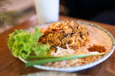 Taze karidesli Pad Thai bir restorandaki ahşap masada yemeye hazır.