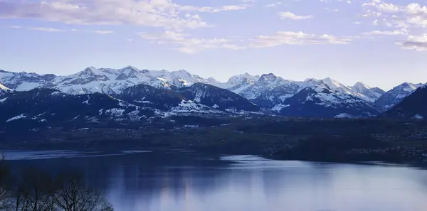 Huzurlu gölü ve karlı tepeleri olan manzaralı dağlık bir yer..