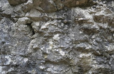 Yıpranmış bir kaya yüzeyinin doğal yakın çekimi kaba doku, çatlaklar ve mineral katmanları arka plan veya jeoloji temaları için mükemmel.