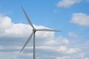 Beyaz bulutlu mavi gökyüzünün arka planında modern rüzgar türbini. Temiz enerji ve çevre dostu teknoloji kavramı