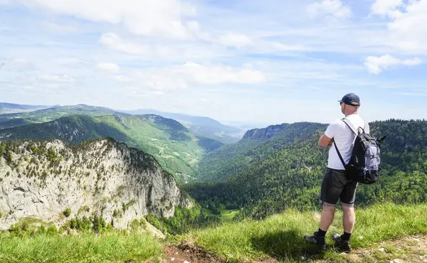 İsviçre 'de yaz yürüyüşü sırasında panoramik dağ manzarası seyreden tek başına bir yürüyüşçü. Yürüyüş kavramı, aktif yaşam tarzı, özgürlük ve doğayla yeniden bağlantı.