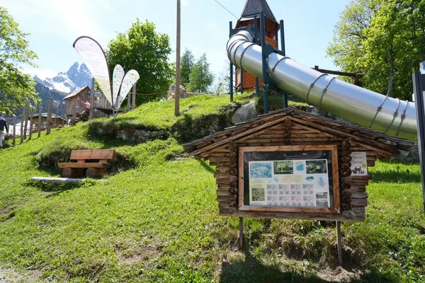 Gimmelwald, İsviçre 'deki çocukların oyun parkında bilgilendirici ahşap bir tahta, metal kayma ve arka planda alp manzarası yer alıyor. Fotoğraf 31 Mayıs 2025 'te çekildi..