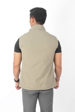 Bir sürü cebi olan bej renkli yelek giyen genç Asyalı adam.