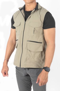 Bir sürü cebi olan bej renkli yelek giyen genç Asyalı adam.