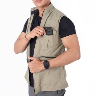 Genç adam cep telefonunu yelek cebine koyuyor.