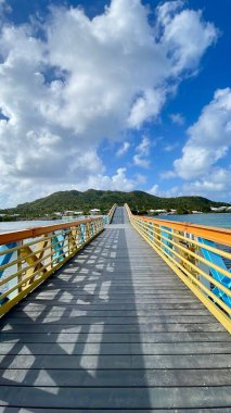 Açık mavi gökyüzü, su ve manzaralı tropikal güneşli adada renkli mavi ve turuncu köprü