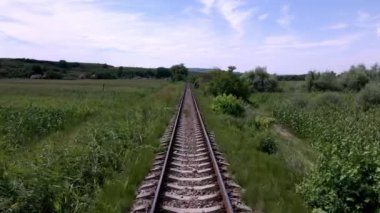 Parlak mavi gökyüzünün altındaki uzak bir Avrupa köyüne doğru uzanan boş tren rayları.