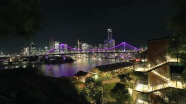 Mor ışıklar, gece gökyüzünde parlayan köprü ve brisbane gökdelenleri aydınlatır. Aydınlatılmış merdivenleri olan kanguru noktası uçurumlarından görülür.