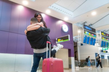 Havaalanında kucaklaşan çift, birbirlerini tekrar gördüklerine sevindiler.