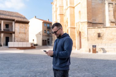 Santa Maria Kilisesi önünde akıllı telefon kullanan genç bir turist. Belediye başkanı, toro, İspanya.. 