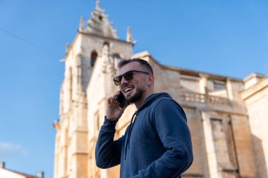 Kilisenin önünde akıllı telefon kullanan bir turist güneşli bir günde telefonla arıyor.