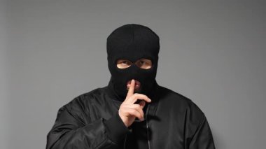 Kar maskesi takmış bir suçlu sessiz bir işaret veriyor.