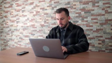 Genç işadamı evde bilgisayar ve akıllı telefon kullanarak çalışıyor.
