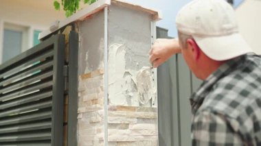 Dış duvarları alçılayan usta inşaat işçileri, ev yenileme işinde profesyonellik ve hassasiyet sergiliyorlar.
