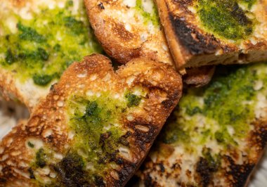 Pesto soslu kızarmış ekmek dilimleri lezzetli ve görsel olarak çekici bir aperatif sunuyor.