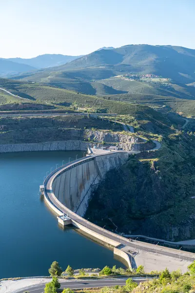 Yeşil dağlarla çevrili Atarazar rezervuarındaki mavi suyu muhafaza eden kavisli beton baraj duvarı Madrid, İspanya 'da hidroelektrik güç üretiyor.