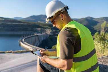 Kalite kontrol mühendisi, barajı incelerken deftere not alıyor.