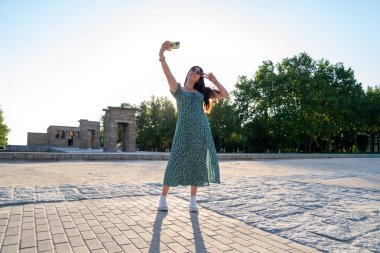 Güneşli bir yaz gününde Madrid, İspanya 'daki debod tapınağının önünde selfie çeken genç bir kadın.