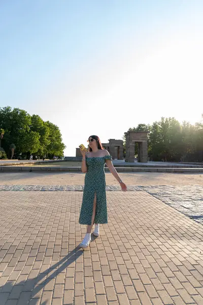 Genç bir kadın yazın Madrid, İspanya 'daki debod tapınağının önünde akıllı telefon kullanıyor, yürüyor ve sesli mesaj kaydediyor.