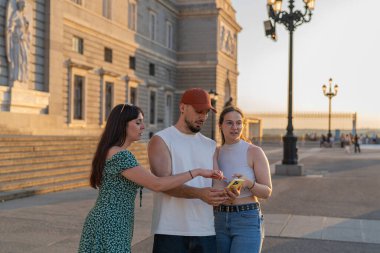 Üç arkadaş, Kraliyet Sarayı 'nın önünde Madrid' de yaz tatilinin tadını çıkarırken akıllı telefonlarına danışırlar.