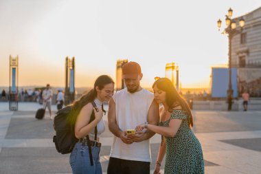 Üç arkadaş yaz tatili sırasında Madrid 'de akıllı bir telefona başvuruyorlar. Güneş batarken canlı atmosferin tadını çıkarıyorlar.