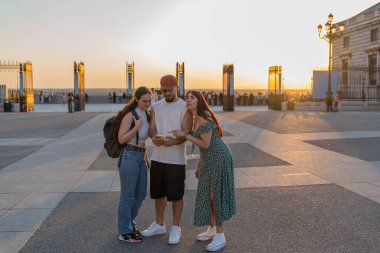 Üç arkadaş yaz tatillerinde Madrid 'de akıllı bir telefona başvuruyorlar. Güzel günbatımının tadını çıkarıyorlar.