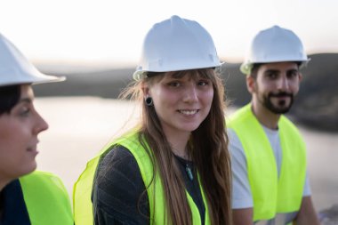 Güvenlik ekipmanı takan gülümseyen mühendisler grubu gençlerin teknik kariyerlerini destekliyor.