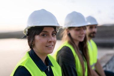 Teknik kariyerleri destekleyen, inşaat alanında çalışan, mühendislik alanında uzmanlık ve profesyonelliği somutlaştıran, çelik yelek ve şapka giyen bir grup mühendis.